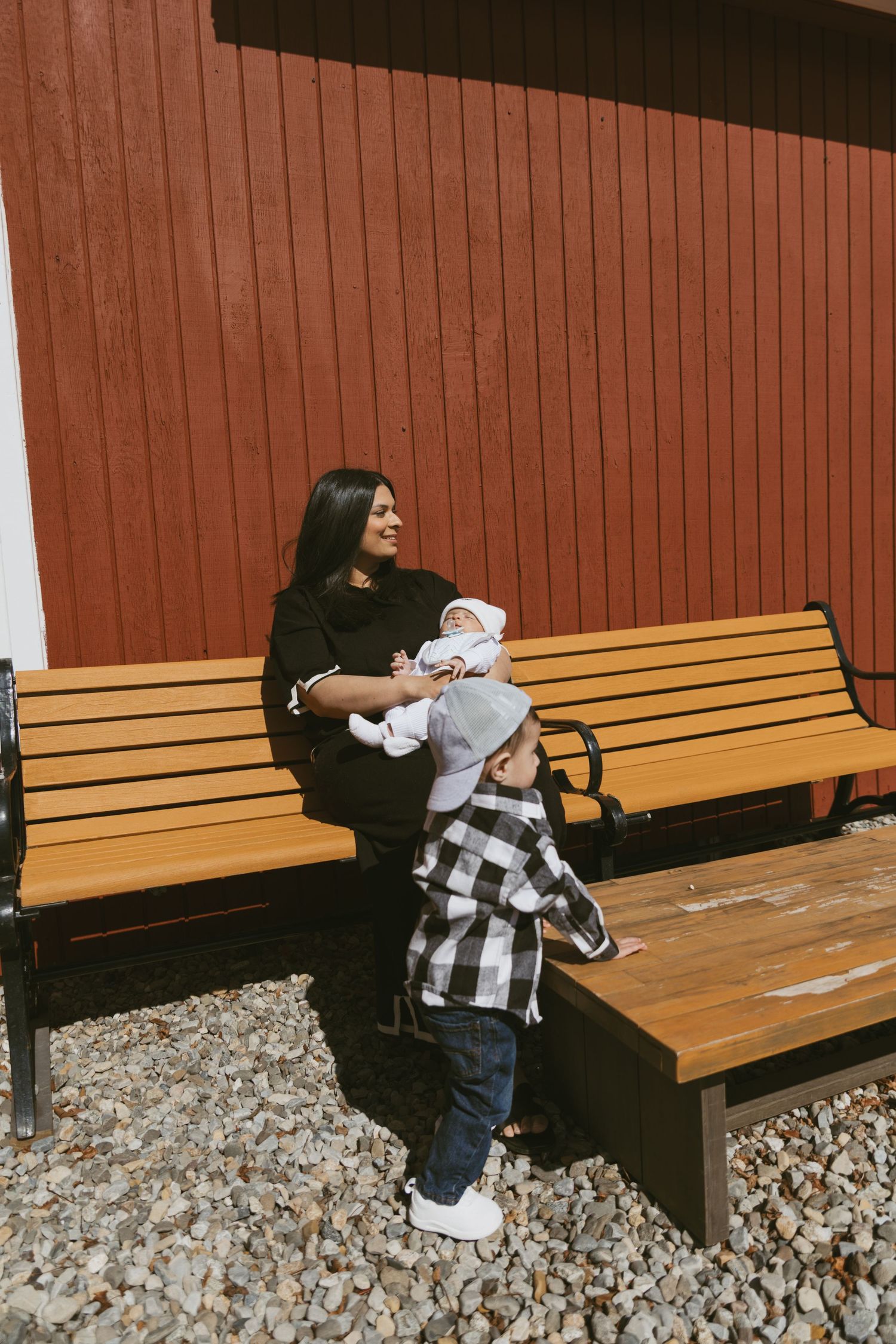 NJ Family documentary lifestyle session. Outside, mom holds her baby watching her toddler play.