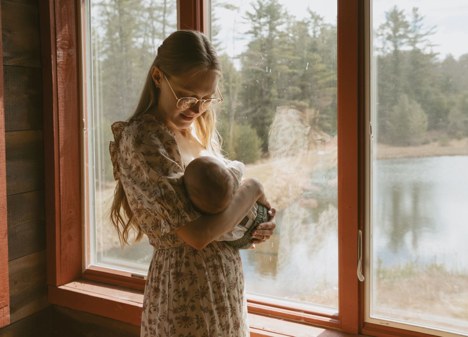 Catskill Mountains New York rustic hunting cabin newborn photos next to window. Mom holding baby