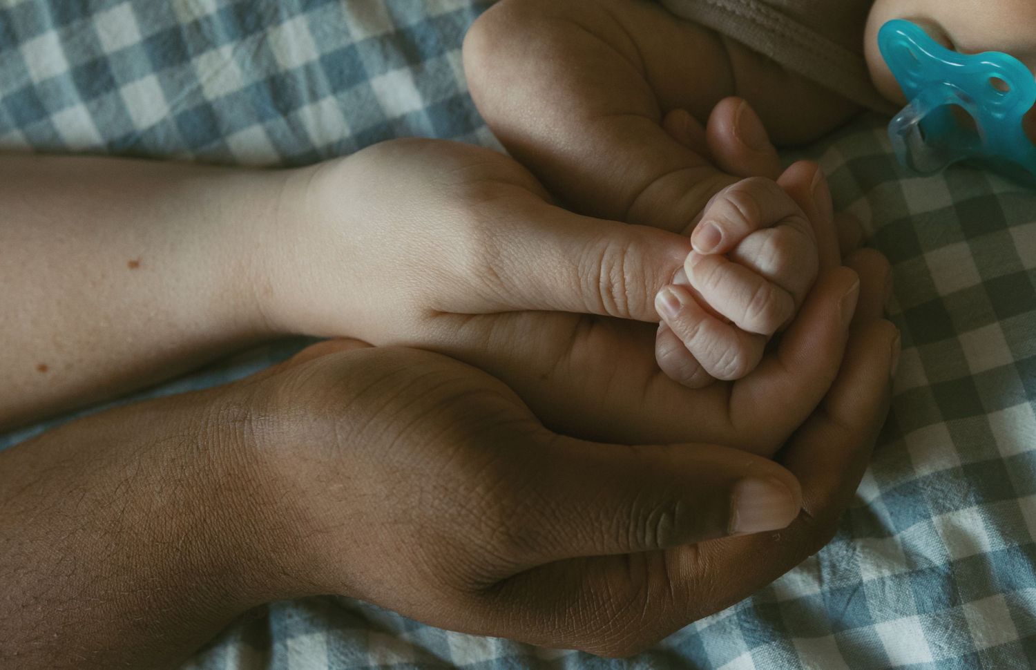 Indoor documentary Newborn home session. Emotional imagery of a mom and dad holding their newborn baby's hand