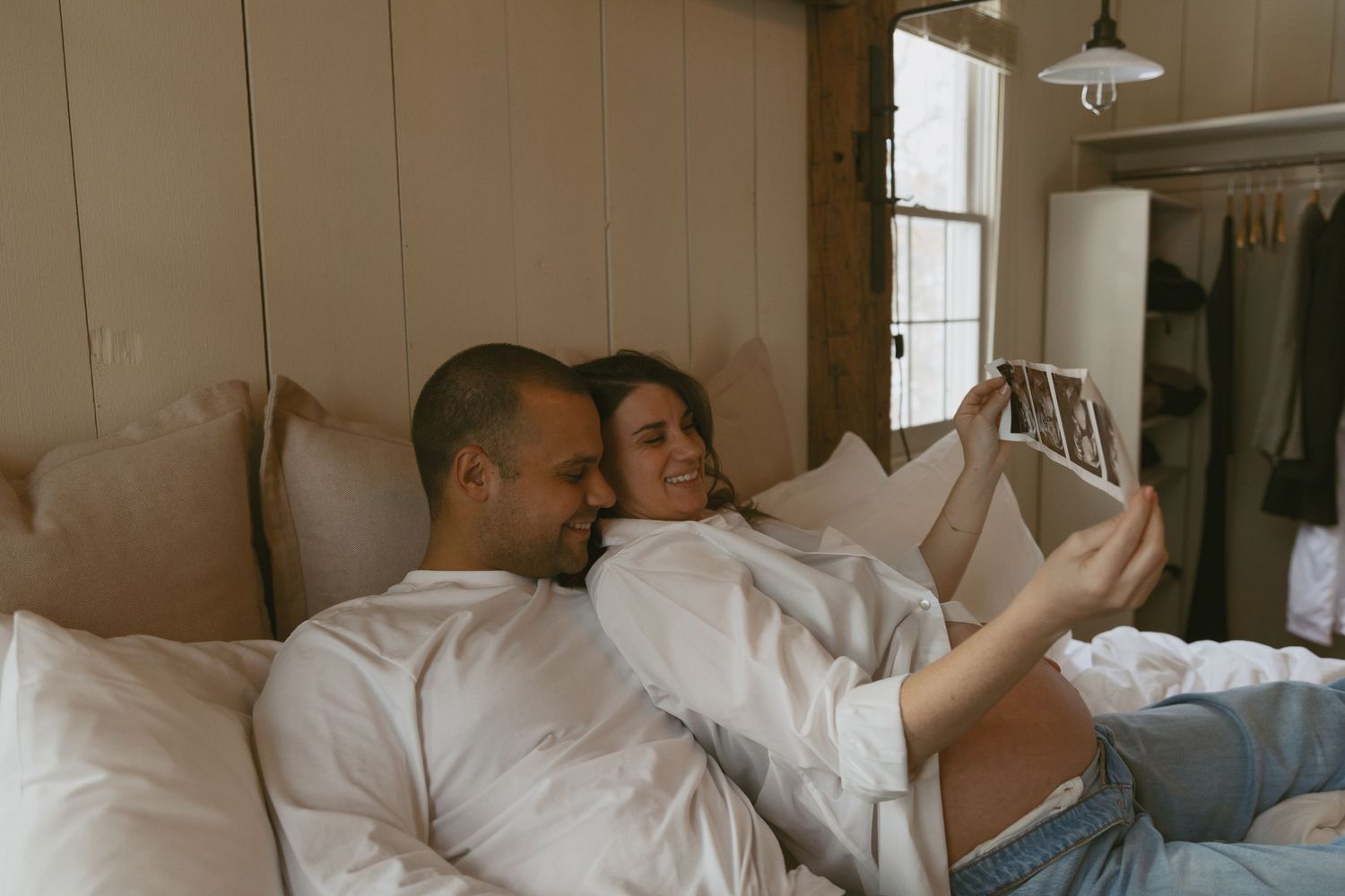 Cozy Editorial indoor maternity photos in the sleepy pine cottage at Cedar Lake Estates in Port Jervis, New York. Holding ultrasound on bed