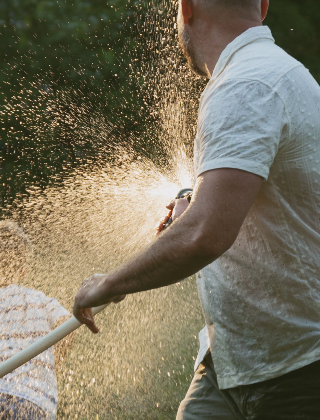 Dad spraying kids with hose during their backyard family photo session in Hudson Valley, New York.