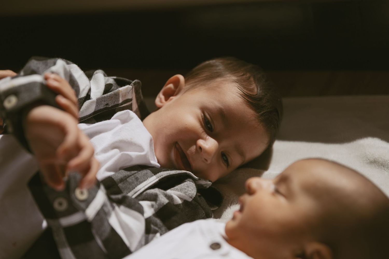 A family lifestyle photoshoot. Toddler and newborn candid photo of them looking at one another.