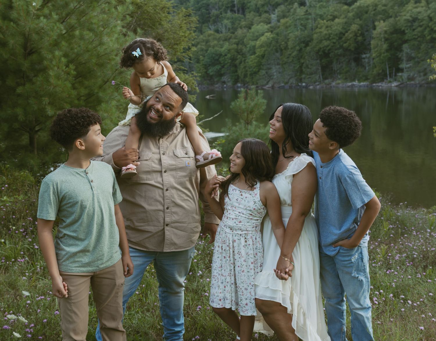 Sullivan County New York, Catskills. Family Photo in a flower field next to water. Family laughing and looking at each other
