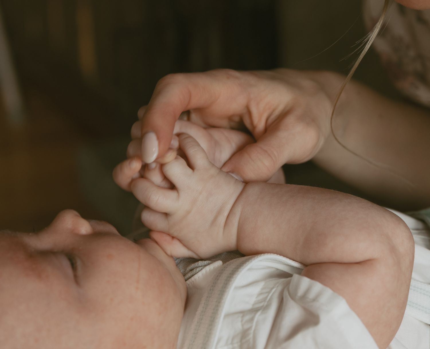 Newborn photos in family cabin in Sullivan County New York, Catskills. Emotive image of details of baby's hands holding moms finger.