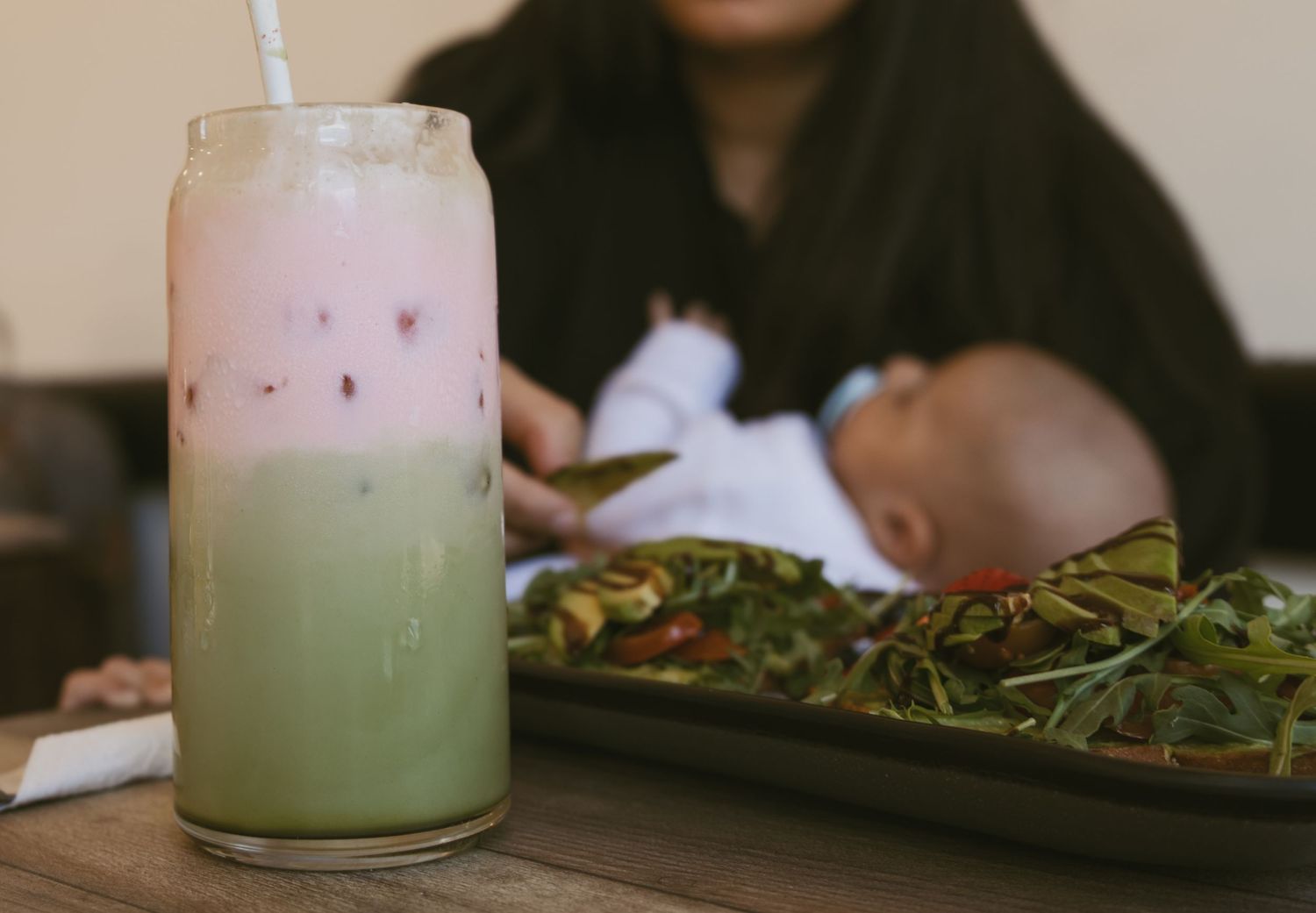 Candid NJ motherhood session. A photo of a mom holding her baby drinking coffee and matcha, taking in the moment.