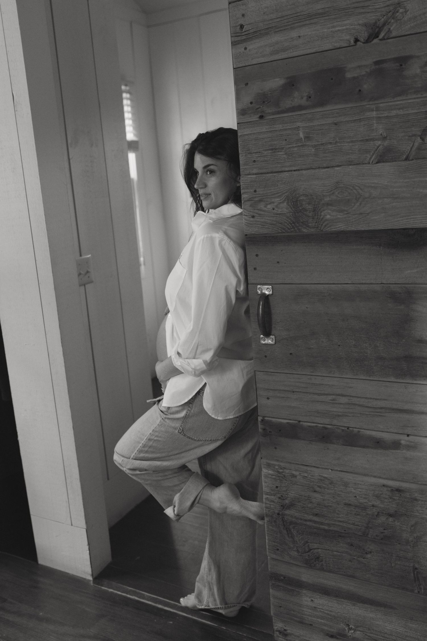 Cozy Editorial indoor maternity photos in the sleepy pine cottage at Cedar Lake Estates in Port Jervis, New York. Leaning against door frame
