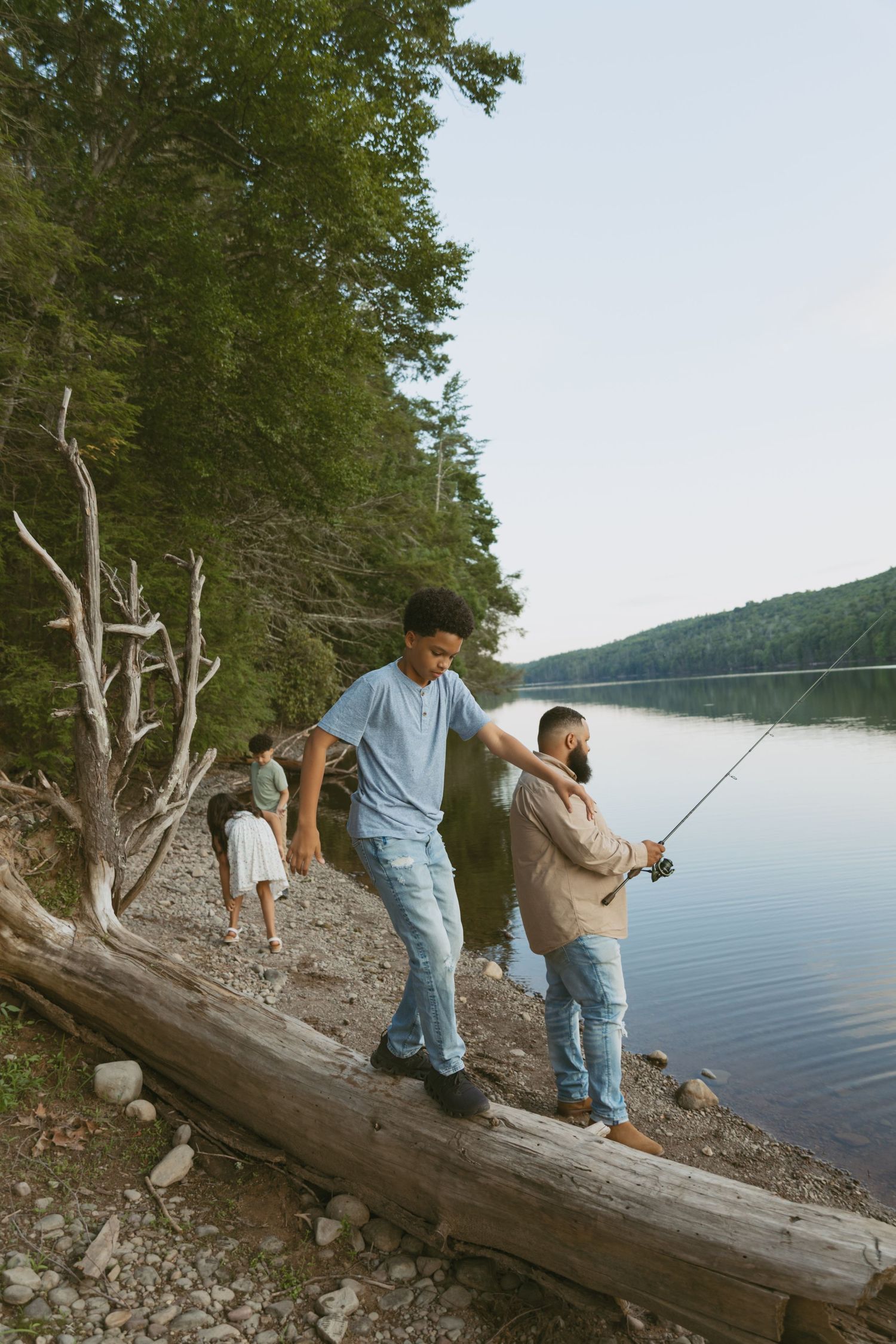 Sullivan County New York, Catskills, Family photos, son walking across fallen tree as siblings fish next to him