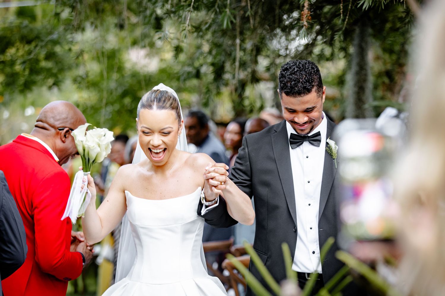 Joyful newlyweds walking back down the aisle laughing after their outdoor wedding ceremony.