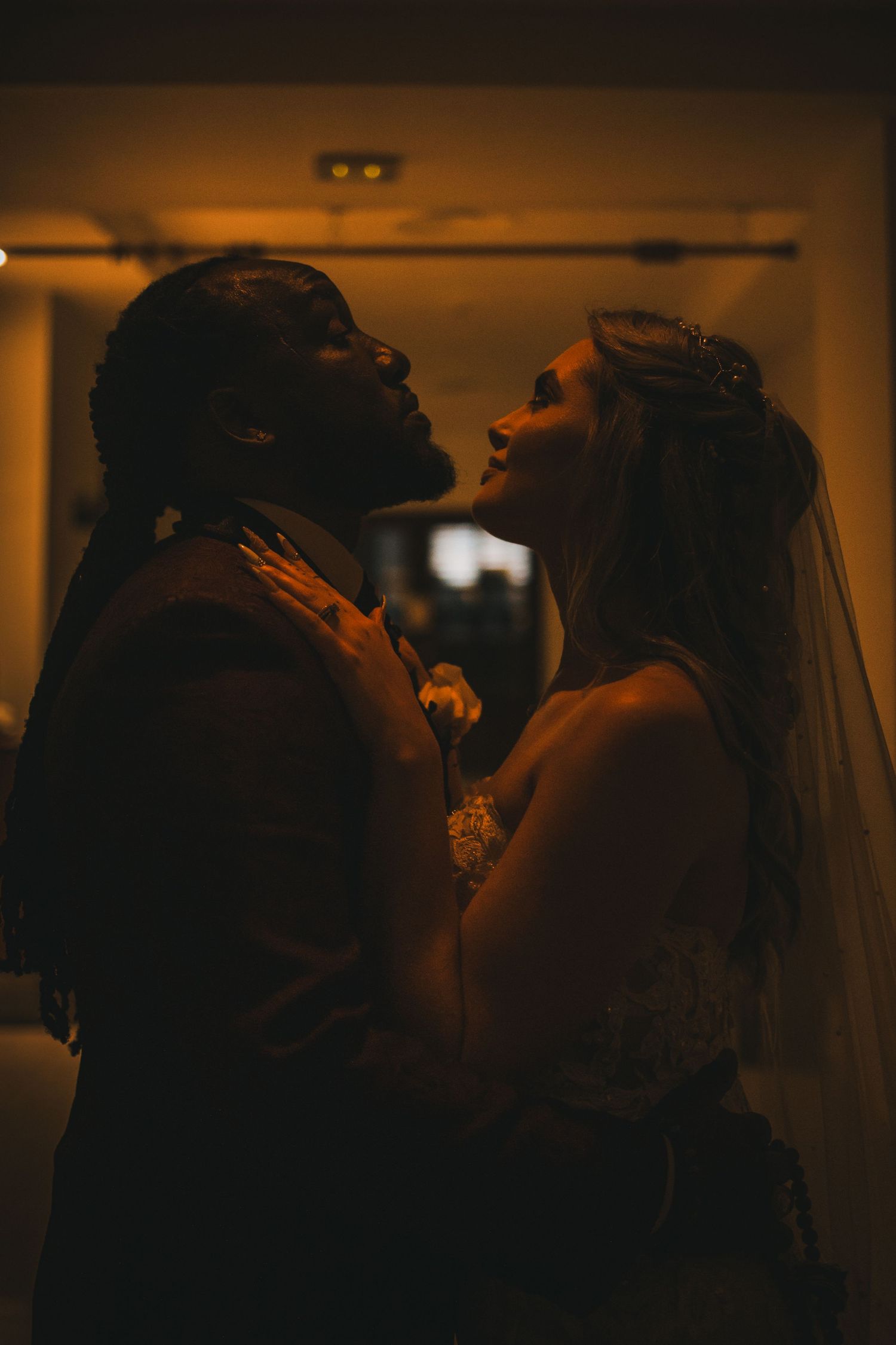 Bride and groom share romantic moment in warm amber light during their wedding celebration.