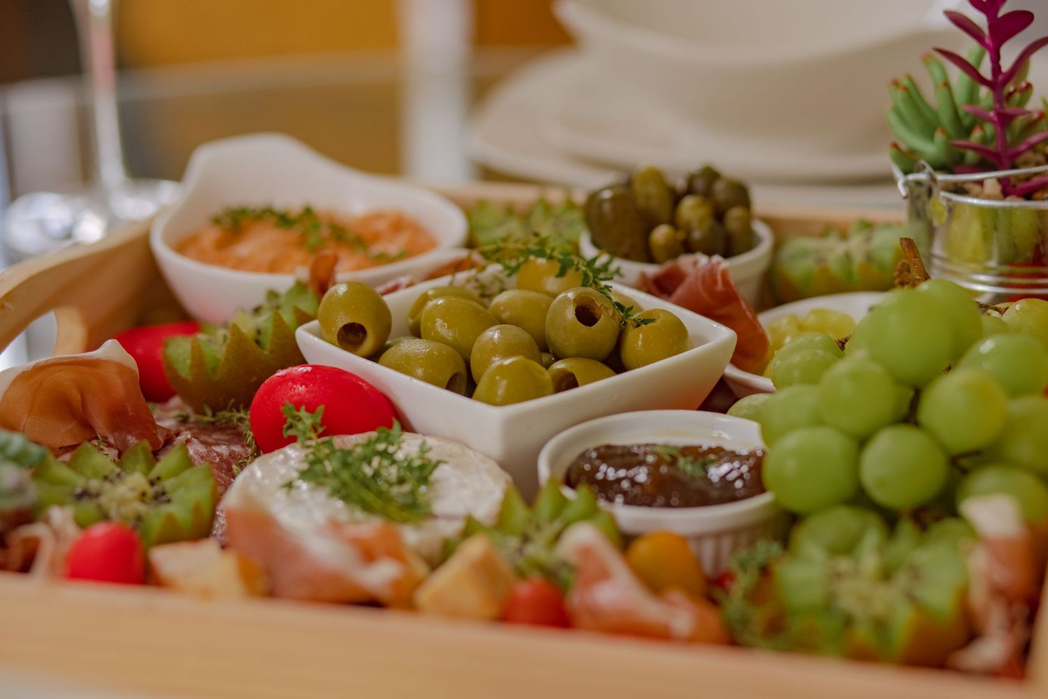 A colorful charcuterie board with olives, grapes, tomatoes, and assorted appetizers for an event.