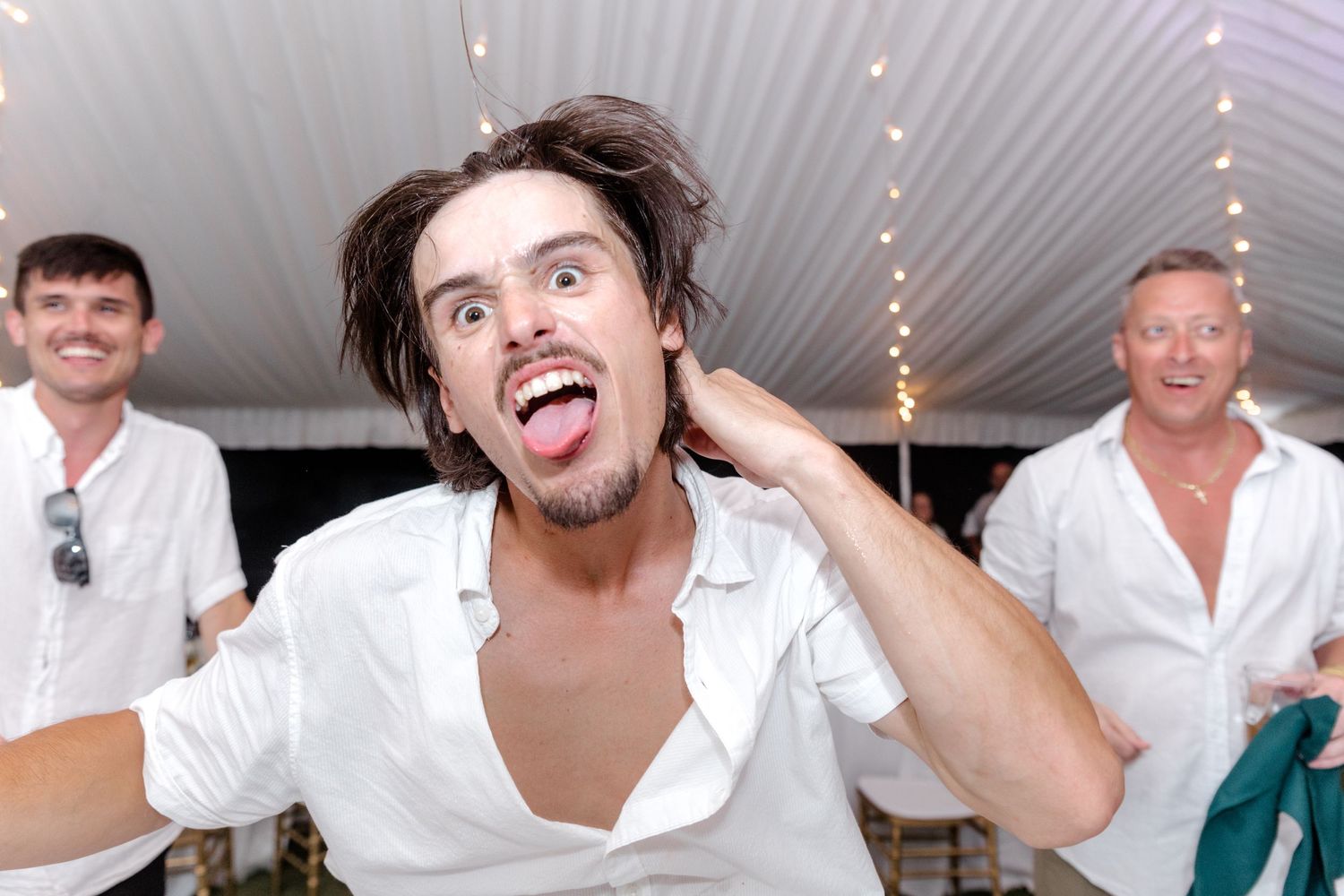 Energetic young man making a funny face while dancing at a wedding reception.