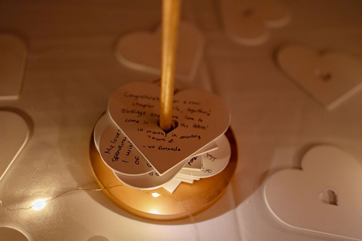 Wooden heart-shaped wedding guest book with handwritten congratulations message on golden stand.