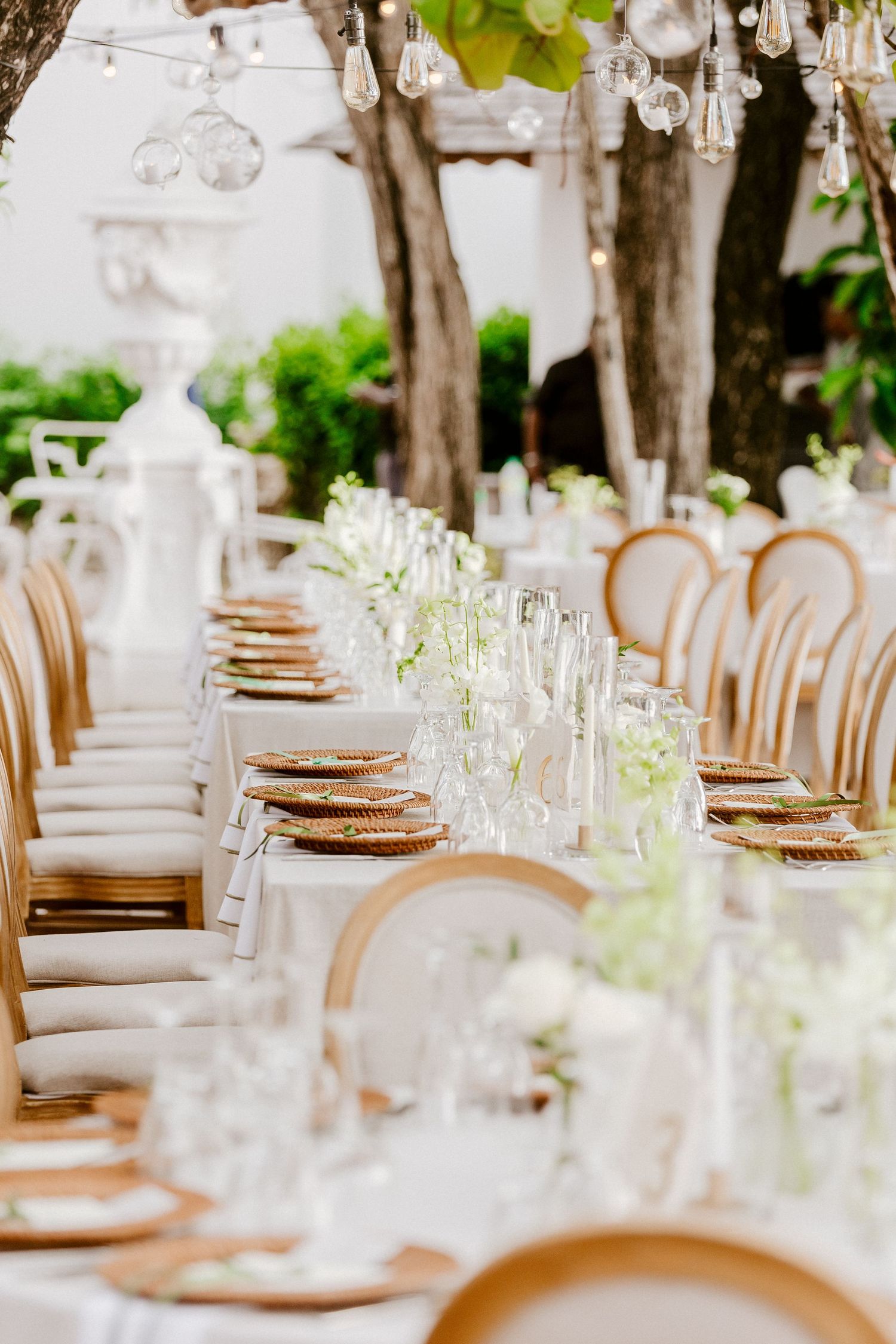 Elegant outdoor wedding reception table with gold chargers, crystal glasses, and white florals.