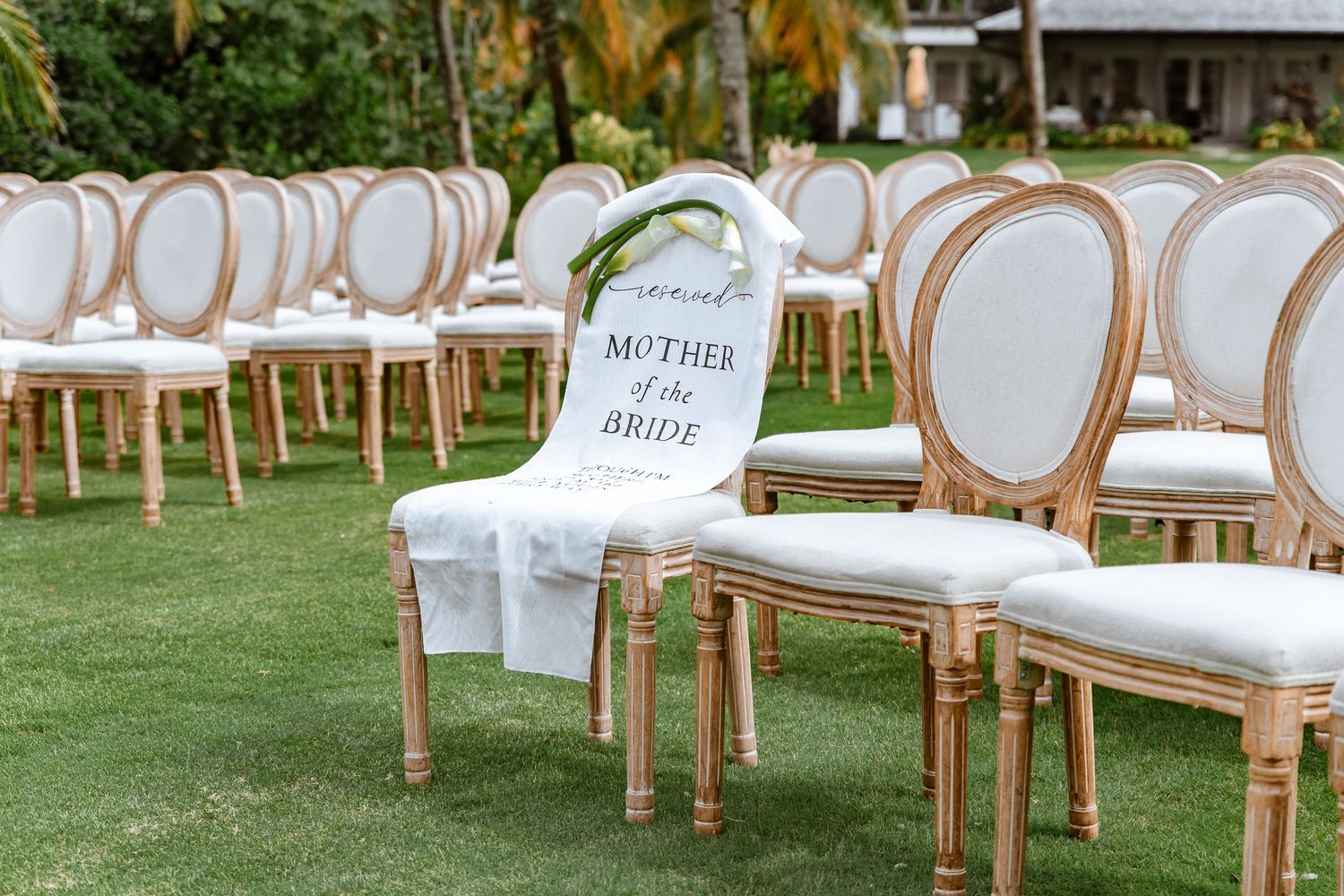 Gold French Louis chairs arranged for outdoor wedding ceremony with Mother of the Bride reserved sign.