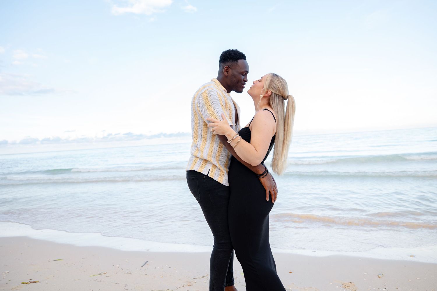 Romantic interracial couple embracing and almost kissing on a serene tropical beach.