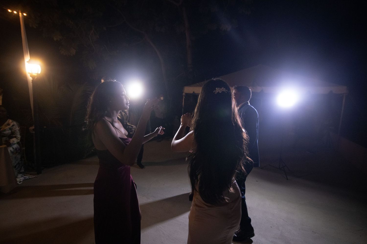 Guests dancing outdoors at night with bright lights illuminating the dark venue.