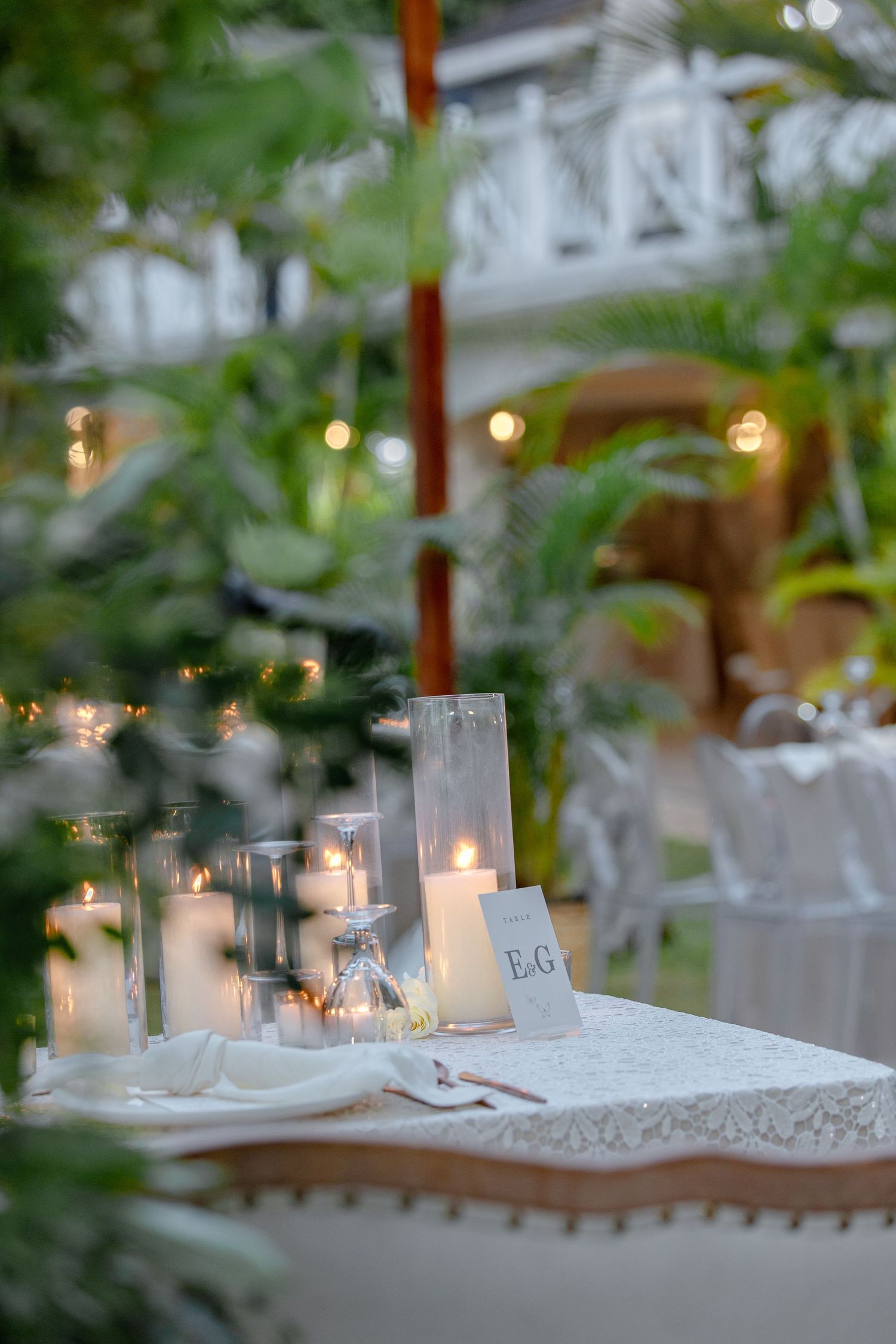 Intimate wedding sweetheart table with monogrammed place card, glowing candles, and string lights backdrop.