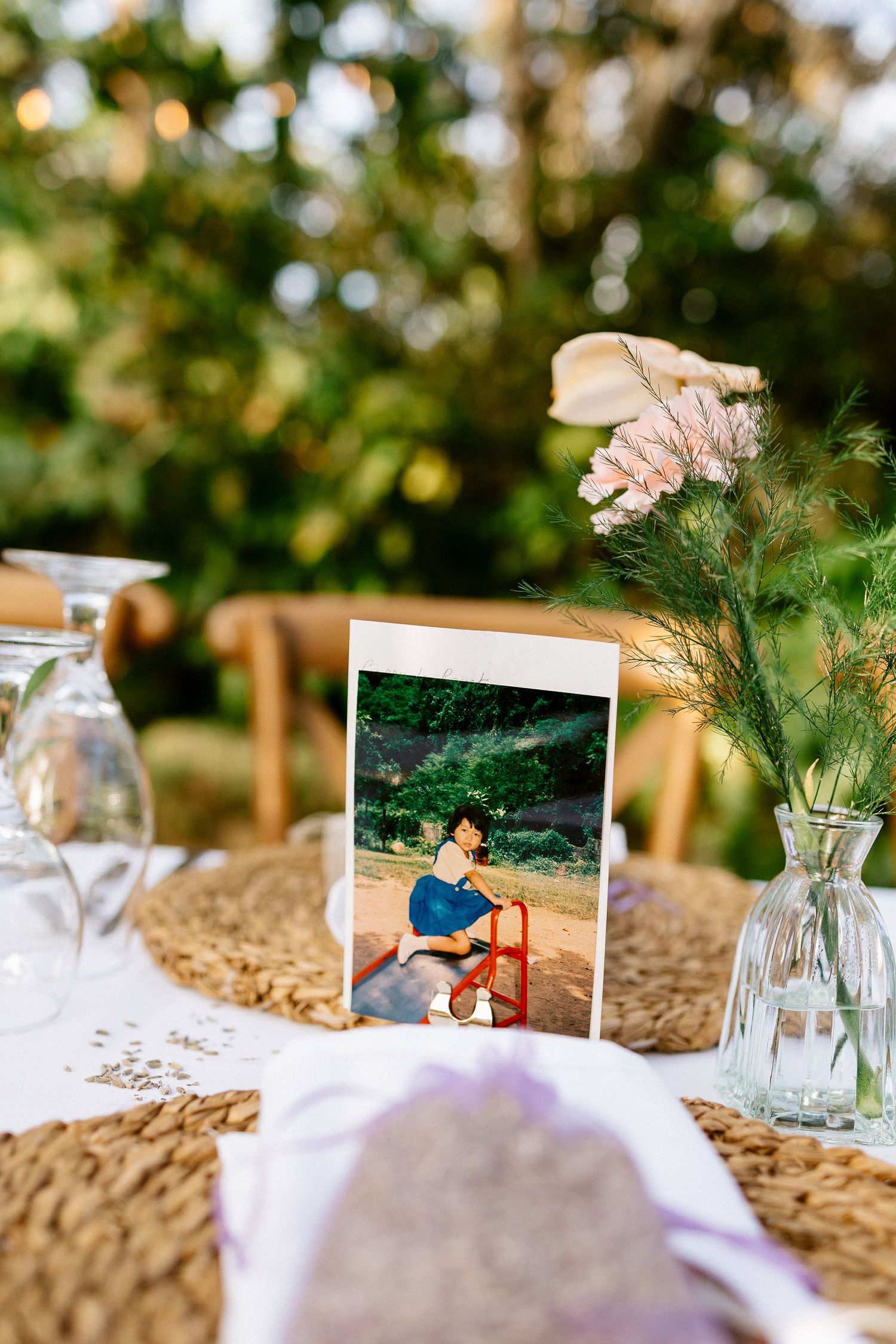 Wedding table decor featuring a polaroid photo card, wildflower arrangement, and woven placemat.