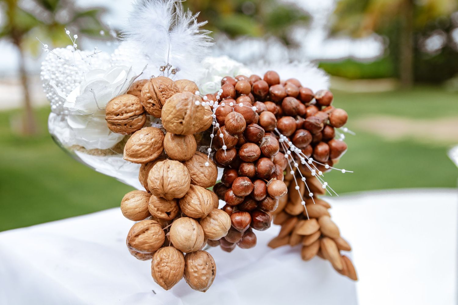 Decorative bouquet of mixed nuts including walnuts, hazelnuts, and almonds with white feather accents.