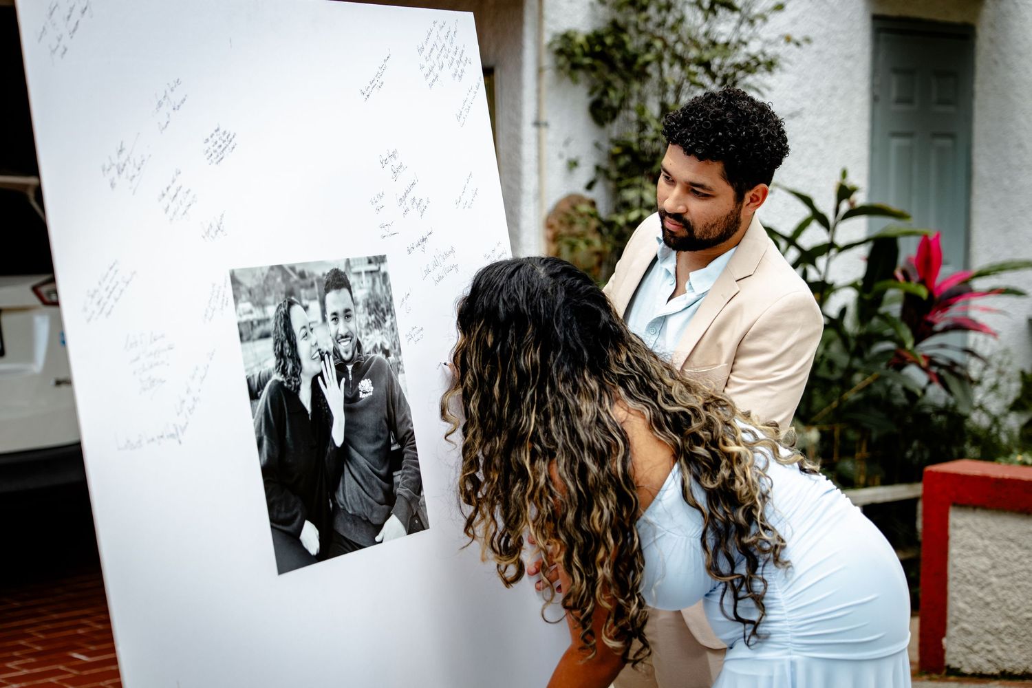 Wedding guests signing a guestbook display featuring a black and white photo of the couple.