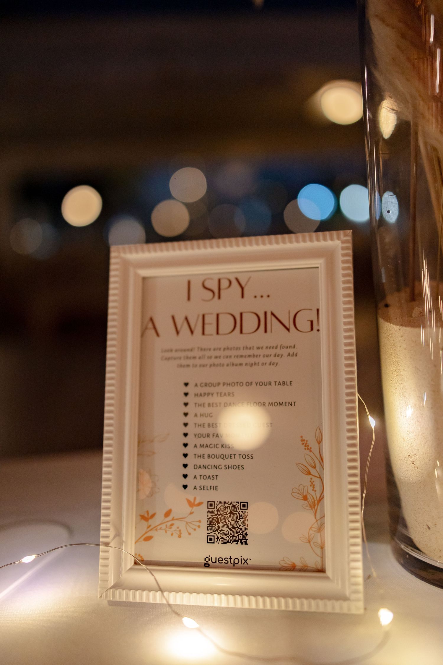 Framed I Spy A Wedding game sign with QR code displayed at wedding reception table decor.
