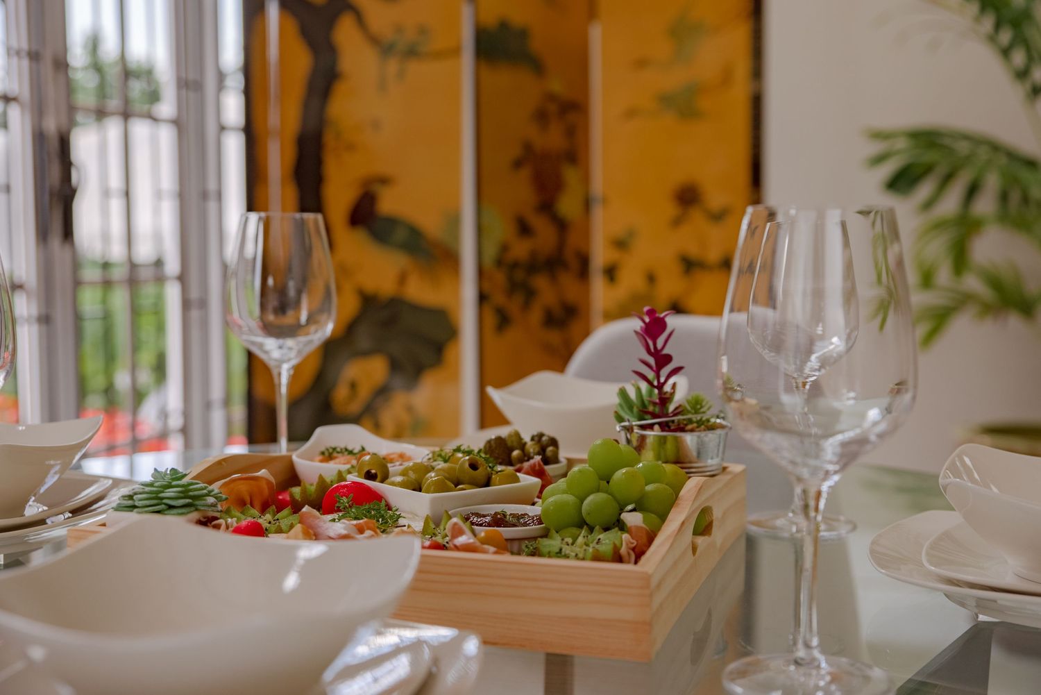 Elegant wedding reception table setting with fresh fruit display, wine glasses, and golden decorative screen.