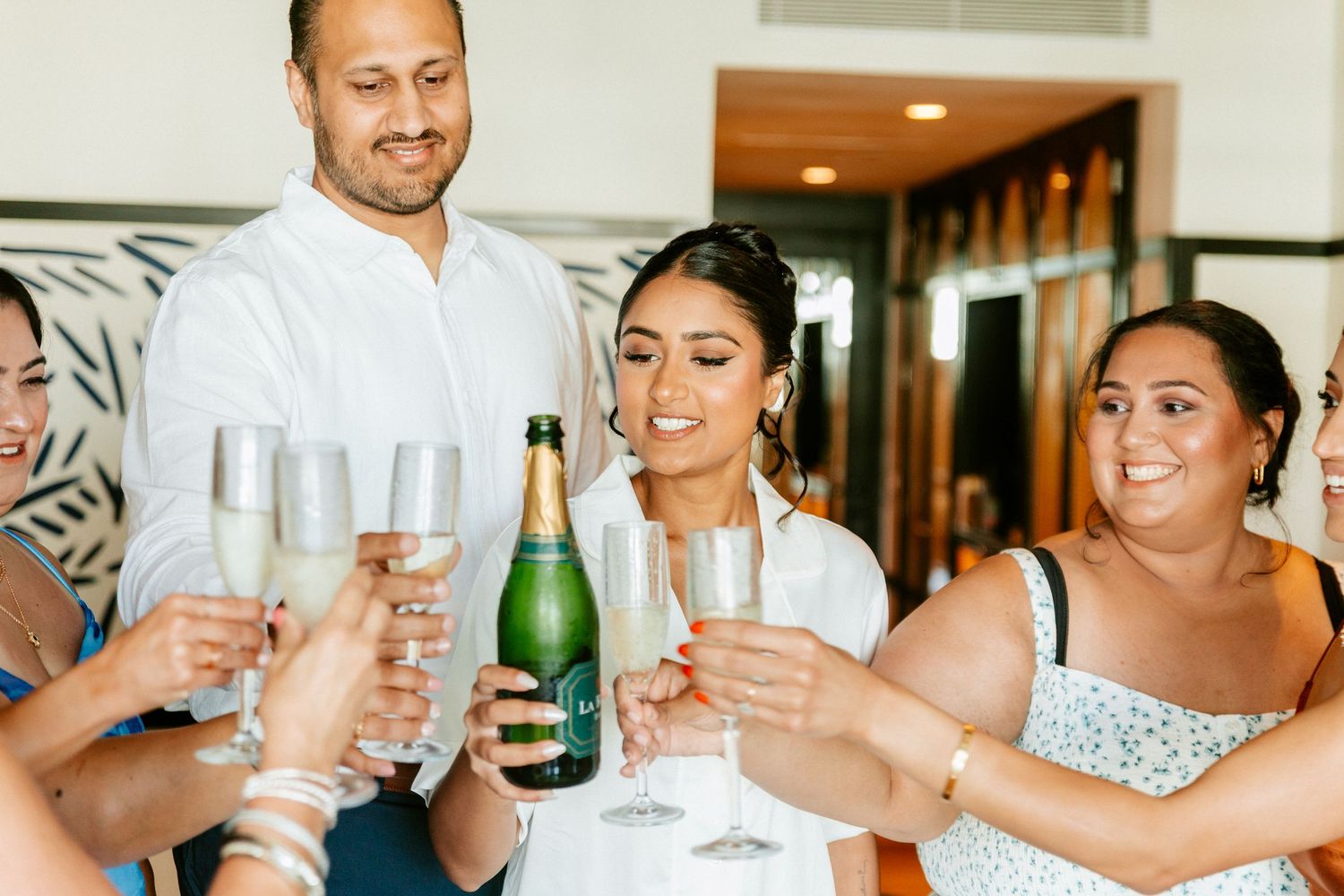 Bride and groom toasting champagne with bridesmaids during wedding celebration.