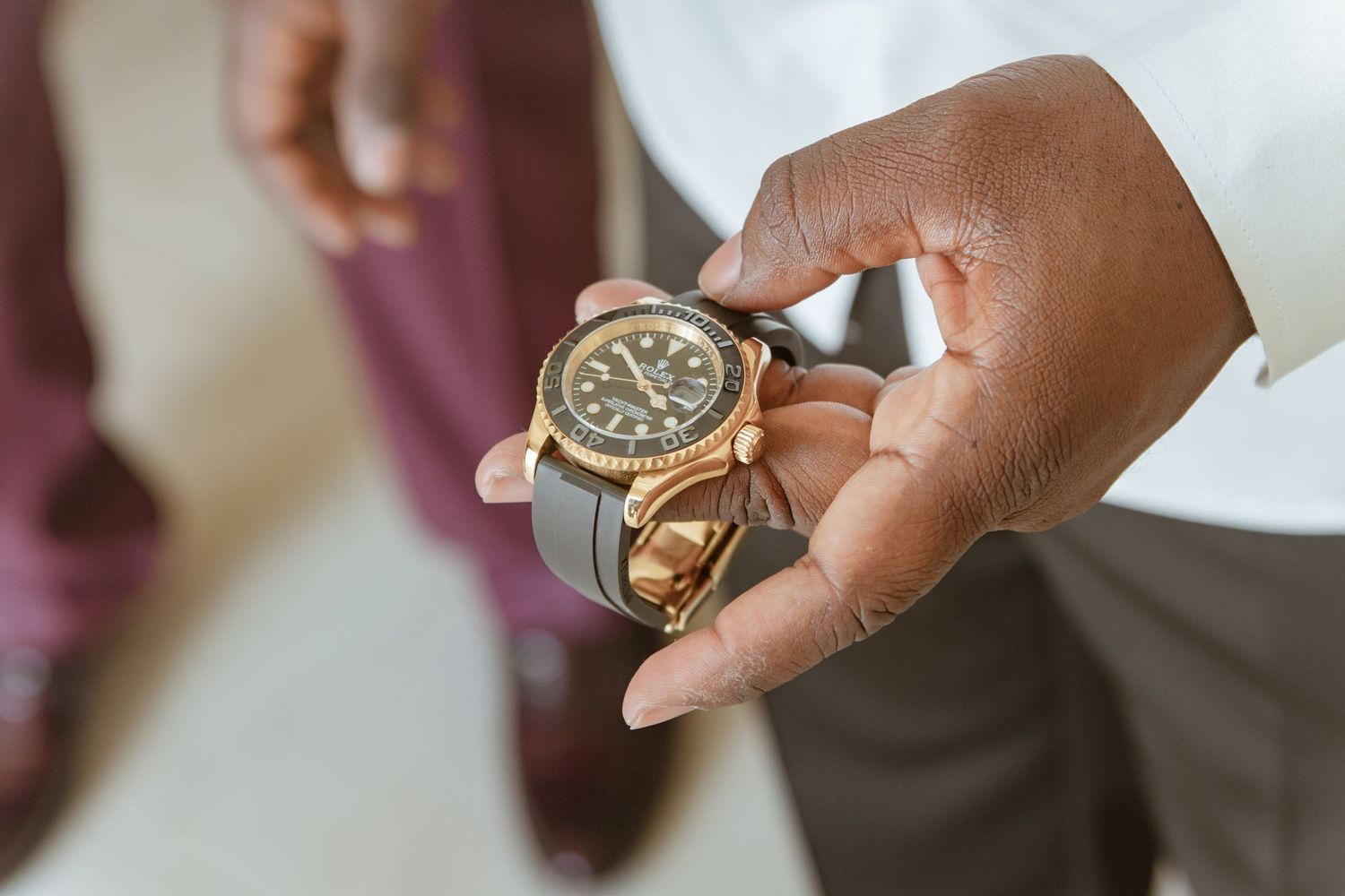 Close-up of hands holding a luxury gold and black diving watch before wedding ceremony.