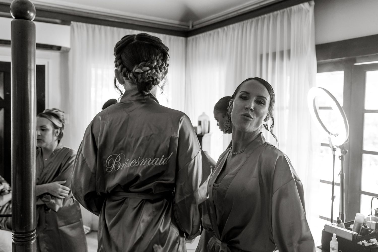 Bridesmaids in satin robes getting ready together before wedding ceremony.