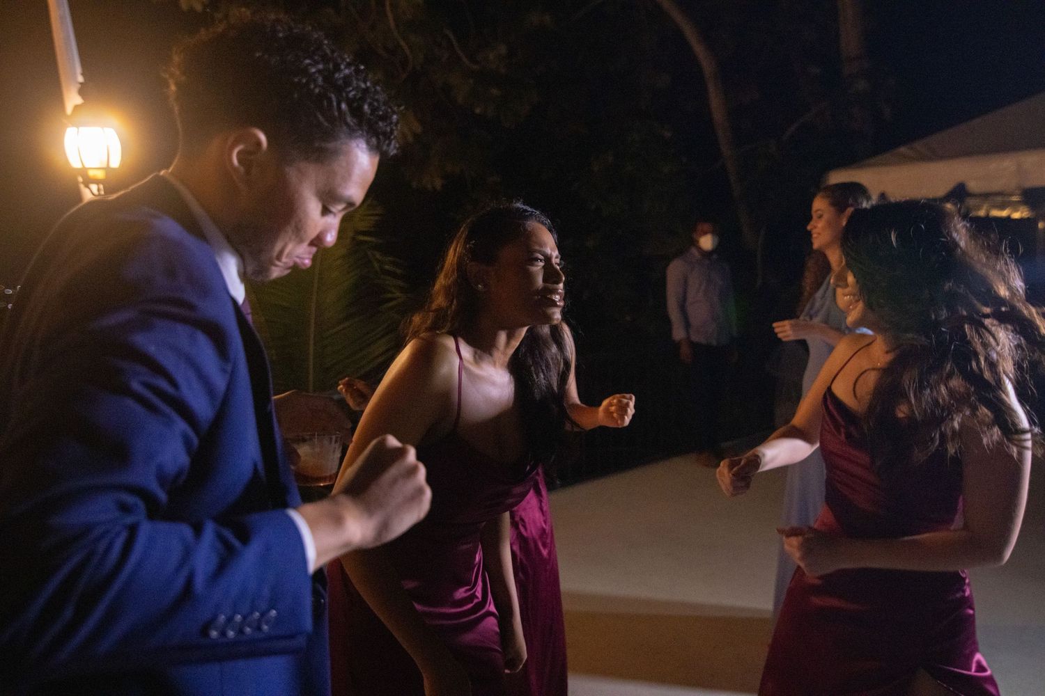Guests in formal attire dancing at an outdoor evening wedding reception.