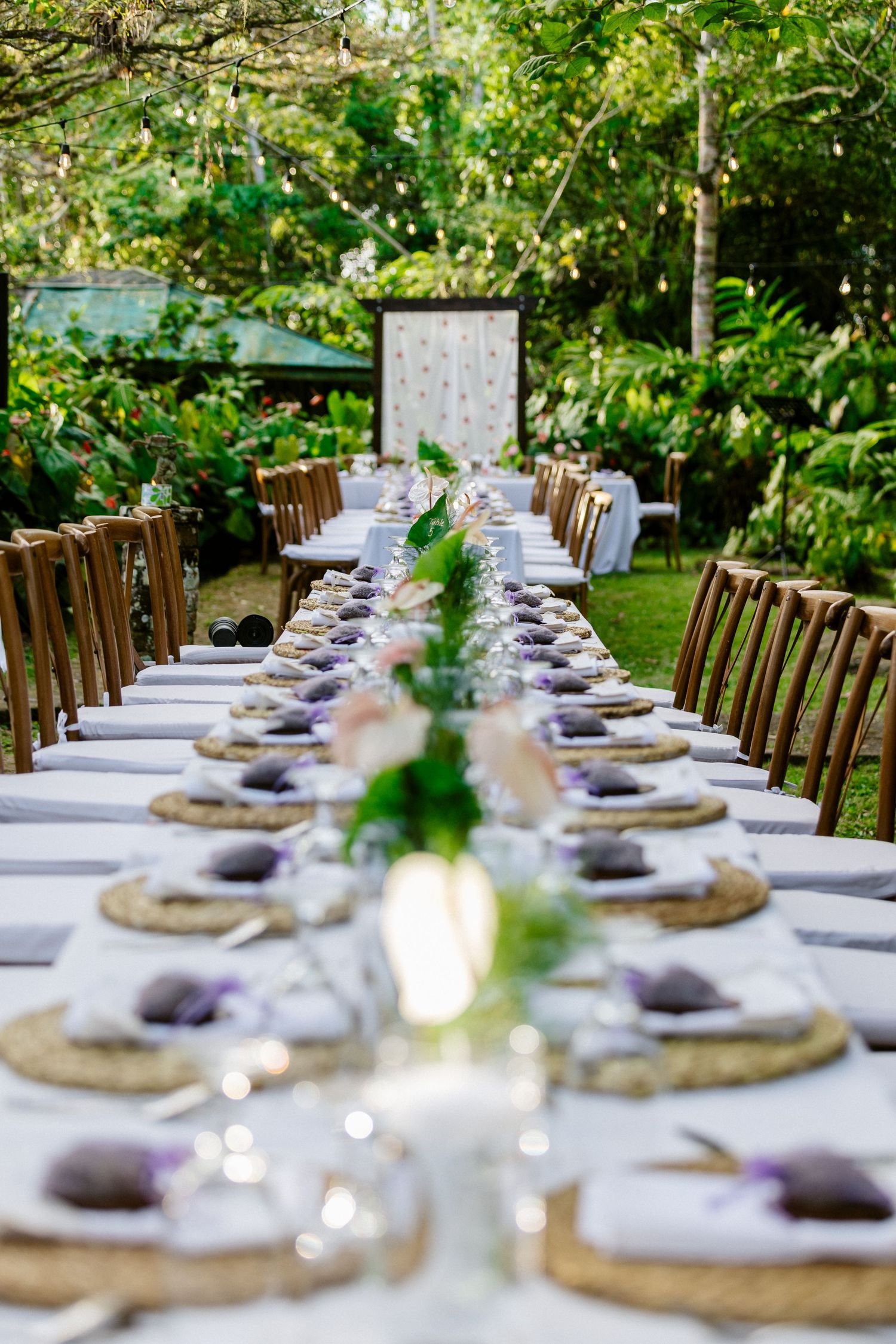 Elegant outdoor wedding reception table set with purple accents and floral centerpieces.