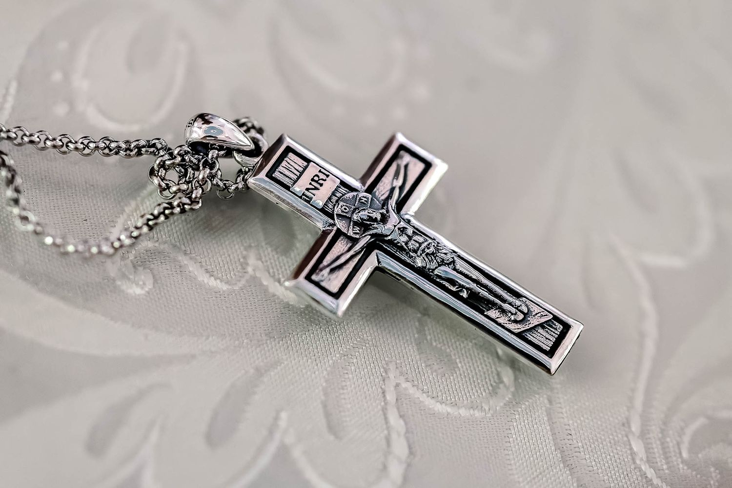 A silver pectoral cross resting on a wooden surface.