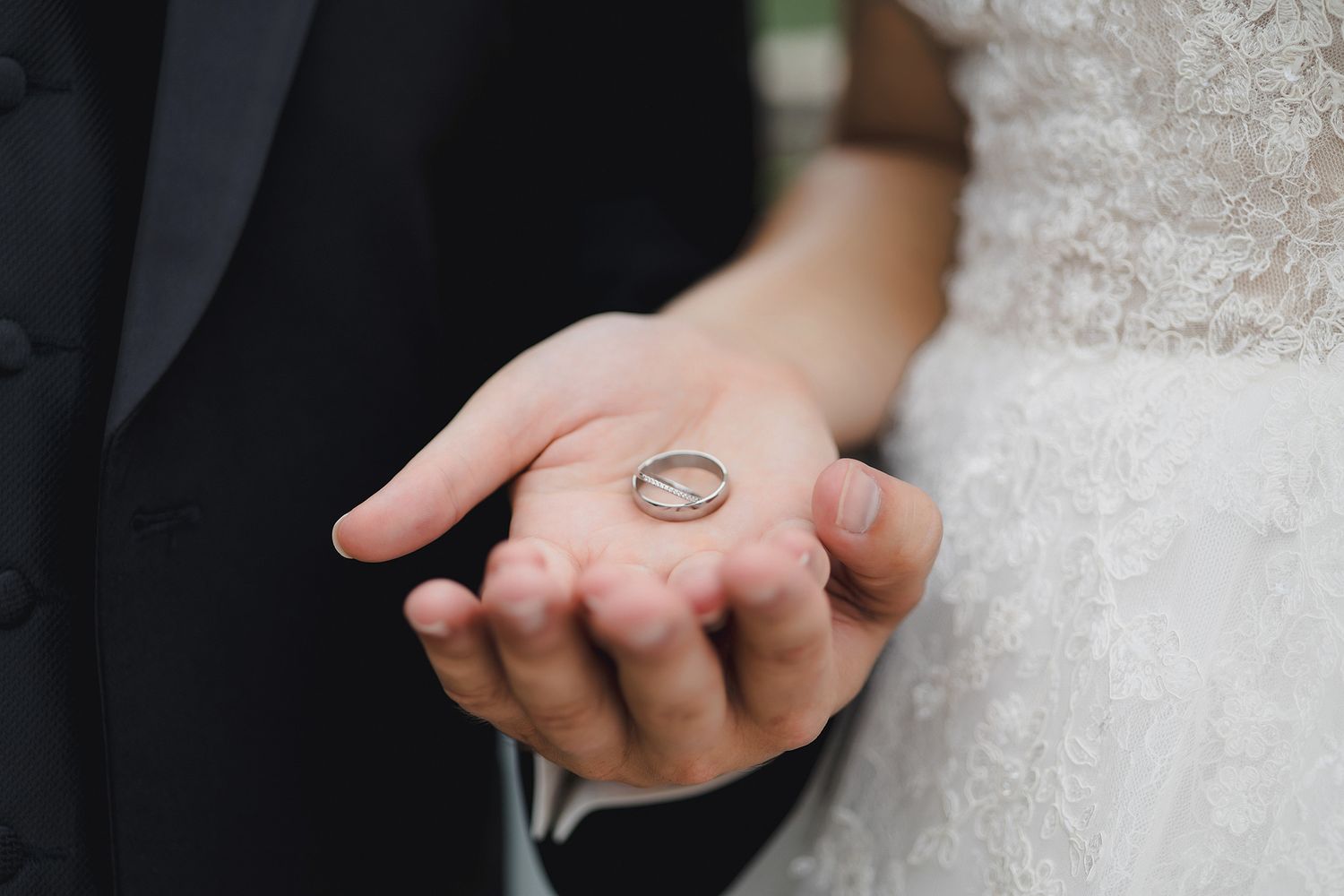 Close-up of hands holding Orthodox wedding rings during a marriage ceremony.