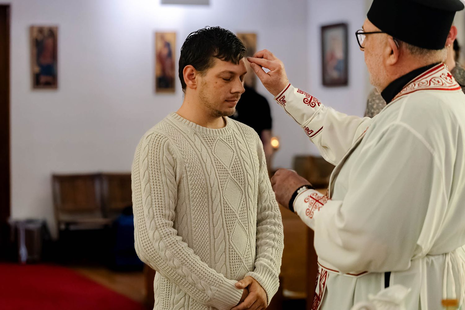 Priest guiding a catechumen during a baptismal service at the font.