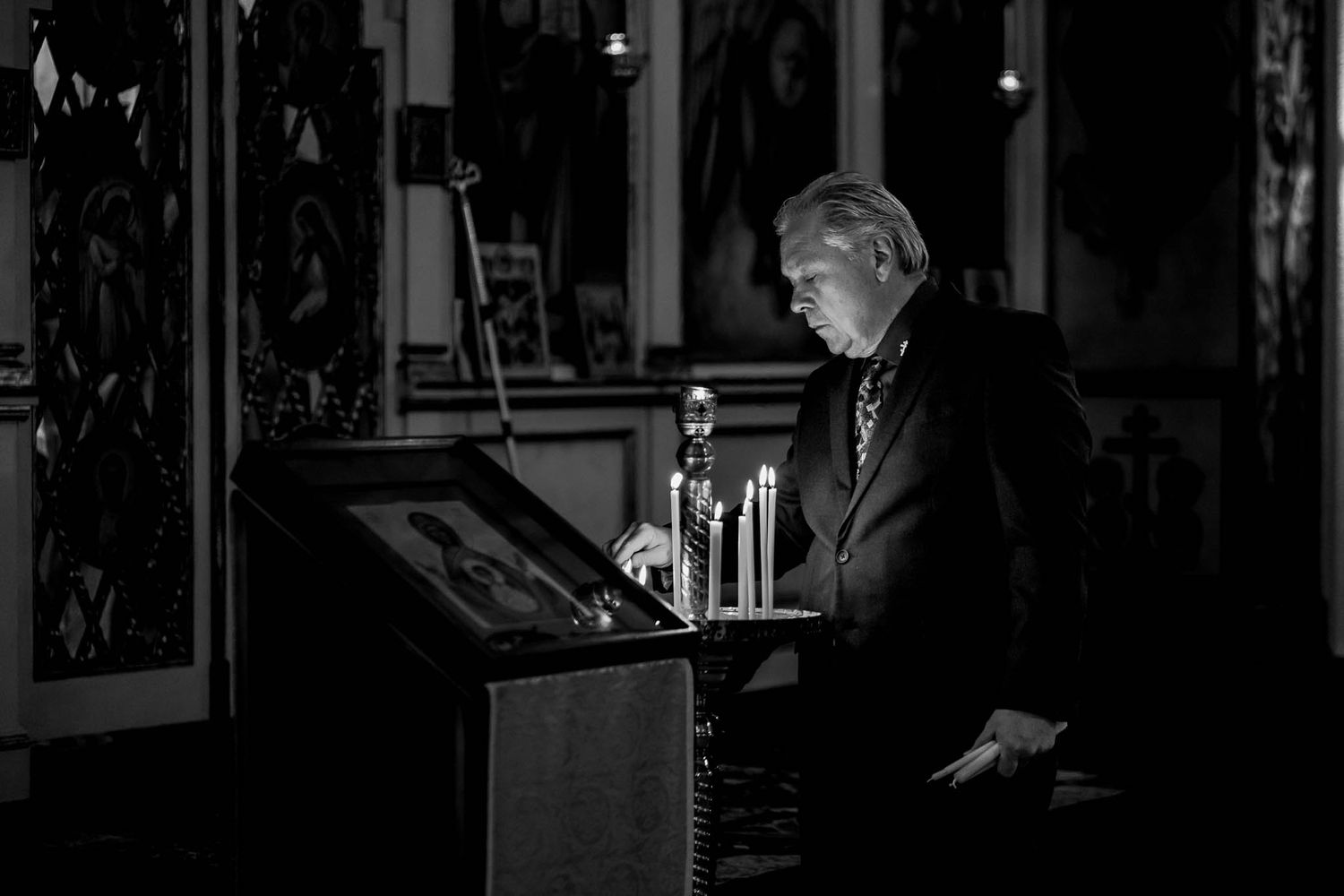 Black and white portrait of an Orthodox parishoner lighting candles before Divine Liturgy.