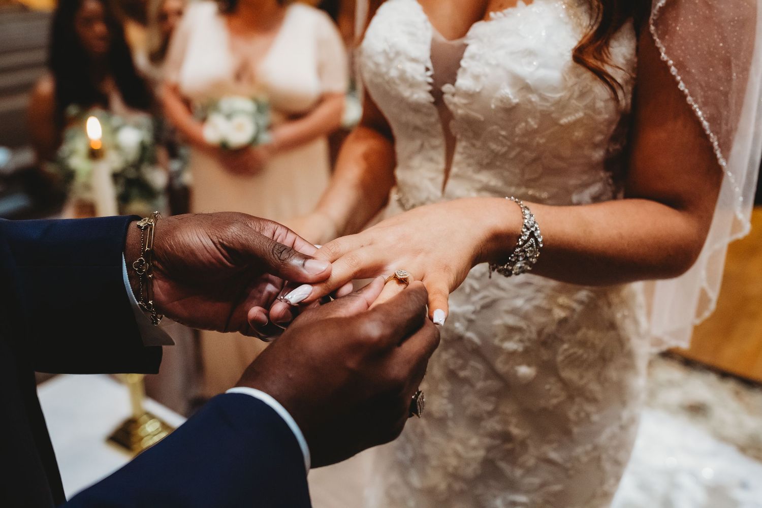 Bride and groom exchanging wedding rings during an intimate ceremony with bridesmaids in background.
