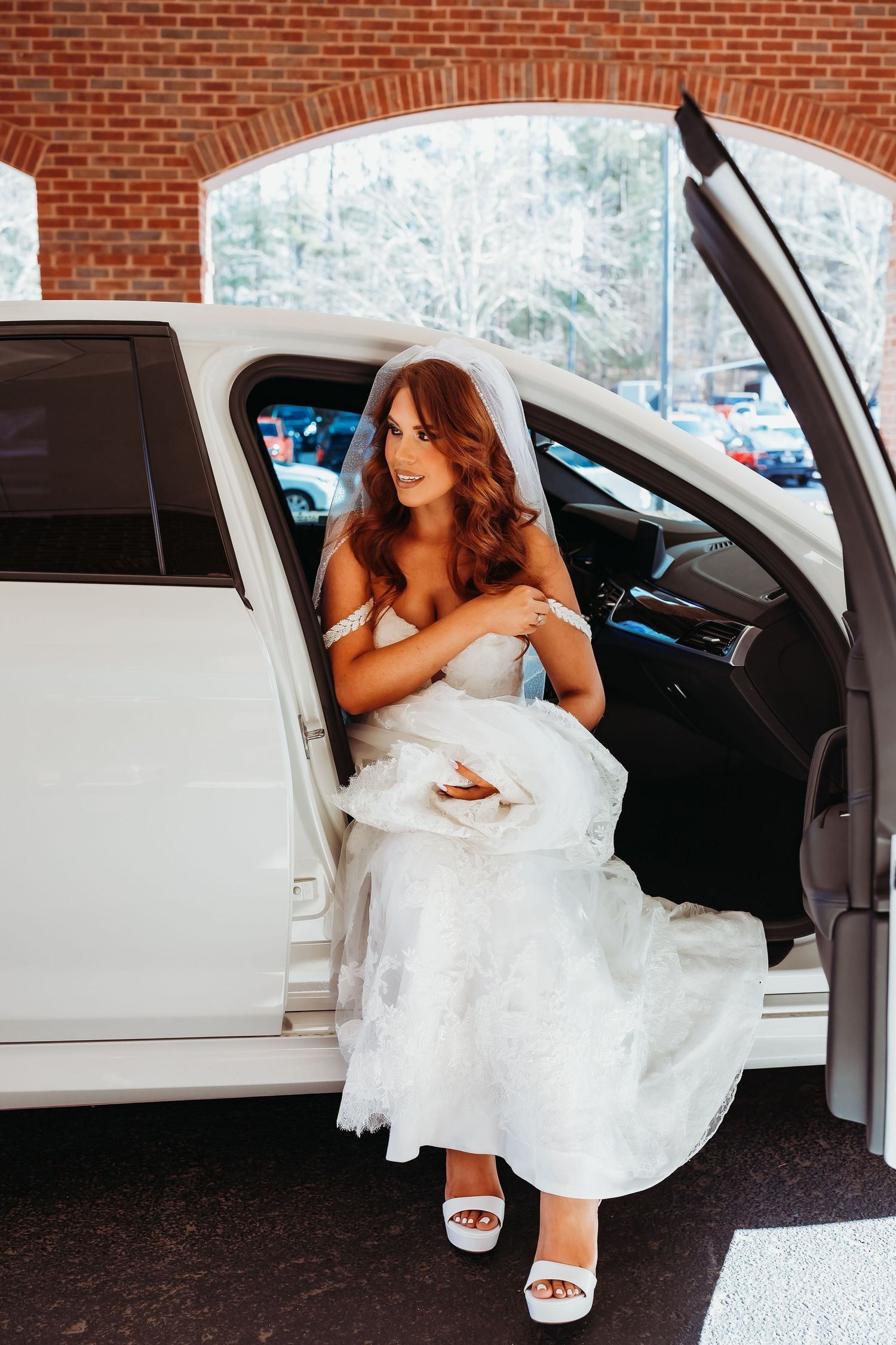 Radiant bride in a strapless wedding gown steps out of a white limousine wearing elegant heeled sandals.