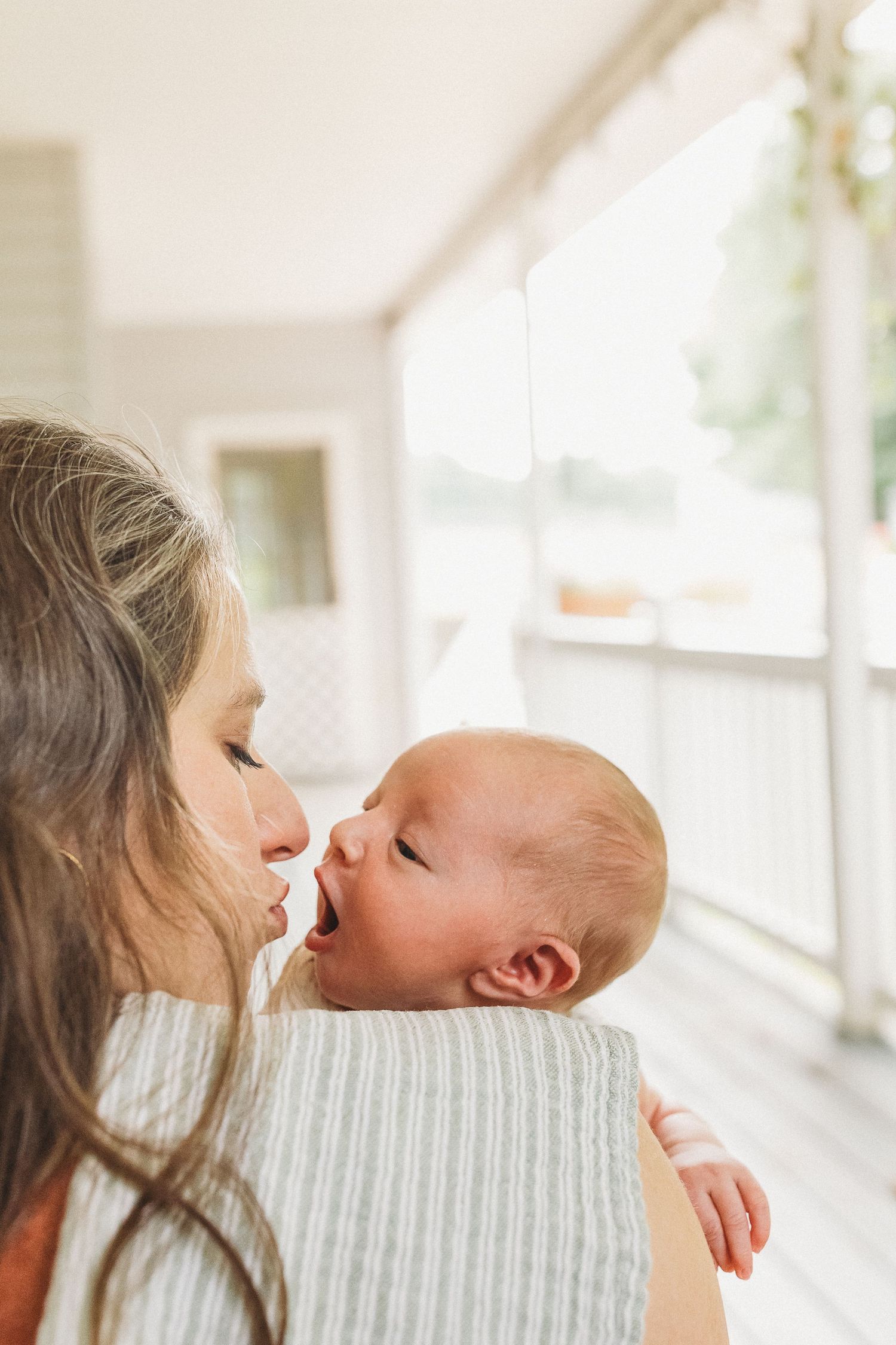 A tender moment as a mother gazes lovingly at her newborn baby, holding the infant close in a bright, airy room.
