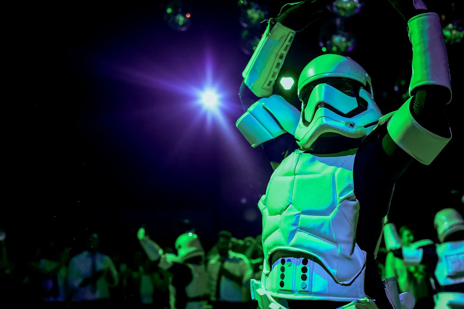 Star Wars Stormtrooper costume dancer glowing under green neon lights at party event.