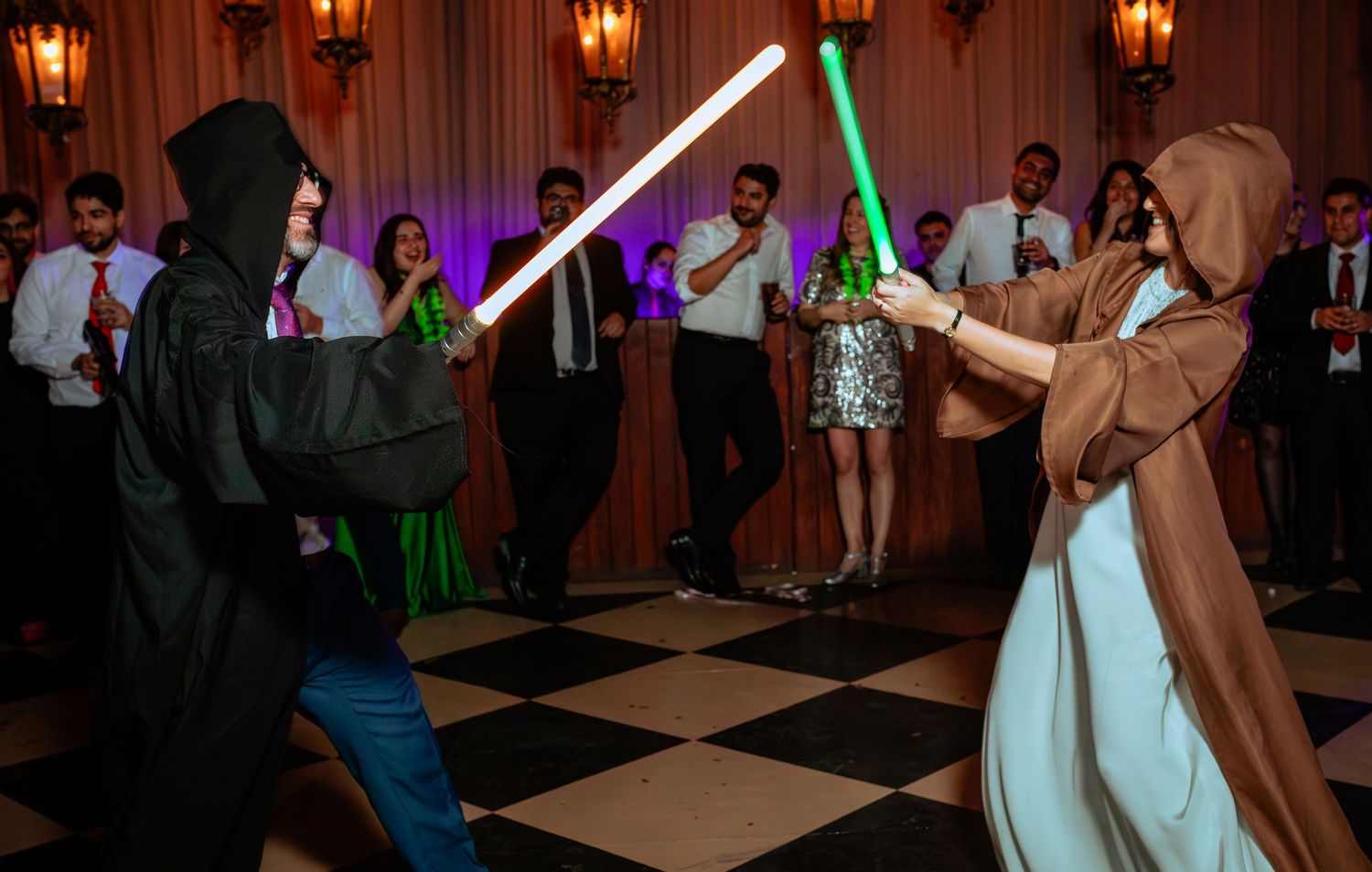 Two guests dressed as Star Wars Jedi and Sith dueling with lightsabers at a wedding reception.