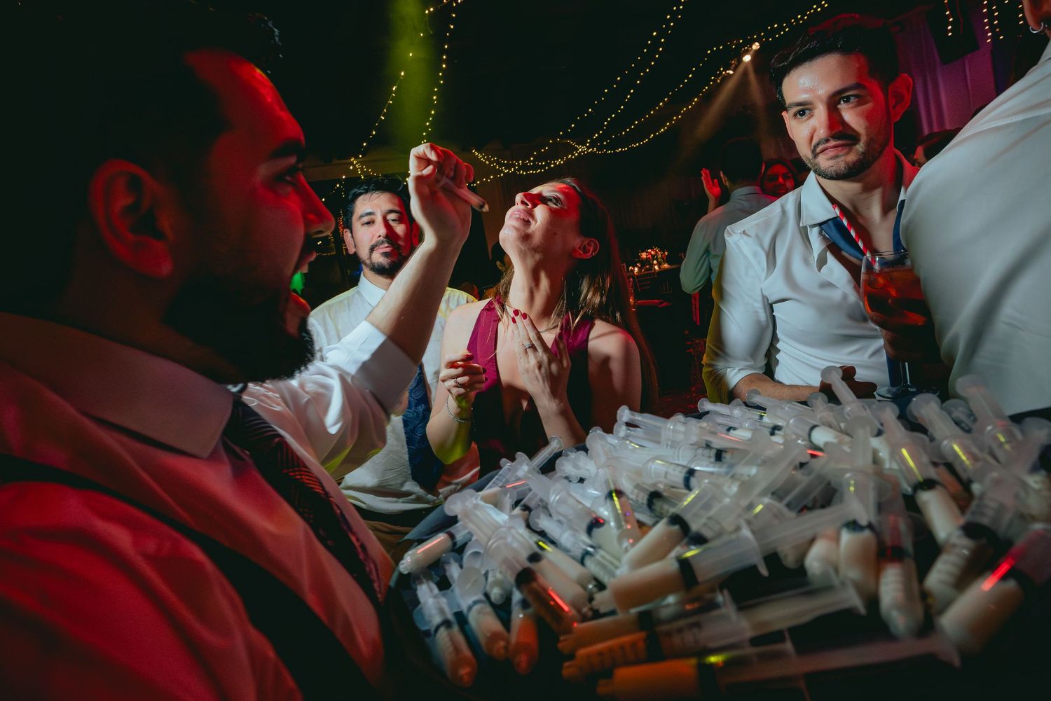 Wedding guests enjoying shots served on a tray at nighttime reception party.