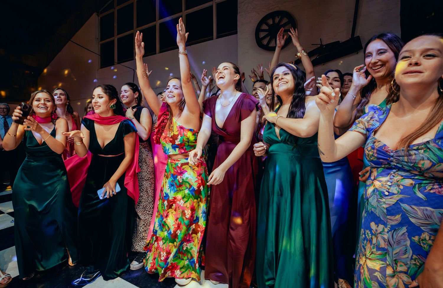 Excited female wedding guests line up eagerly awaiting the bridal bouquet toss.