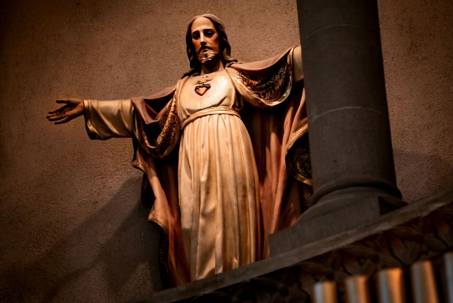 Ornate wooden statue of Jesus Christ with open arms in a historic church.