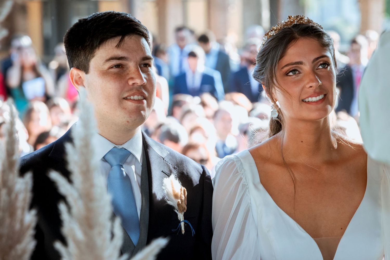 Smiling bride and groom stand together during outdoor wedding ceremony.
