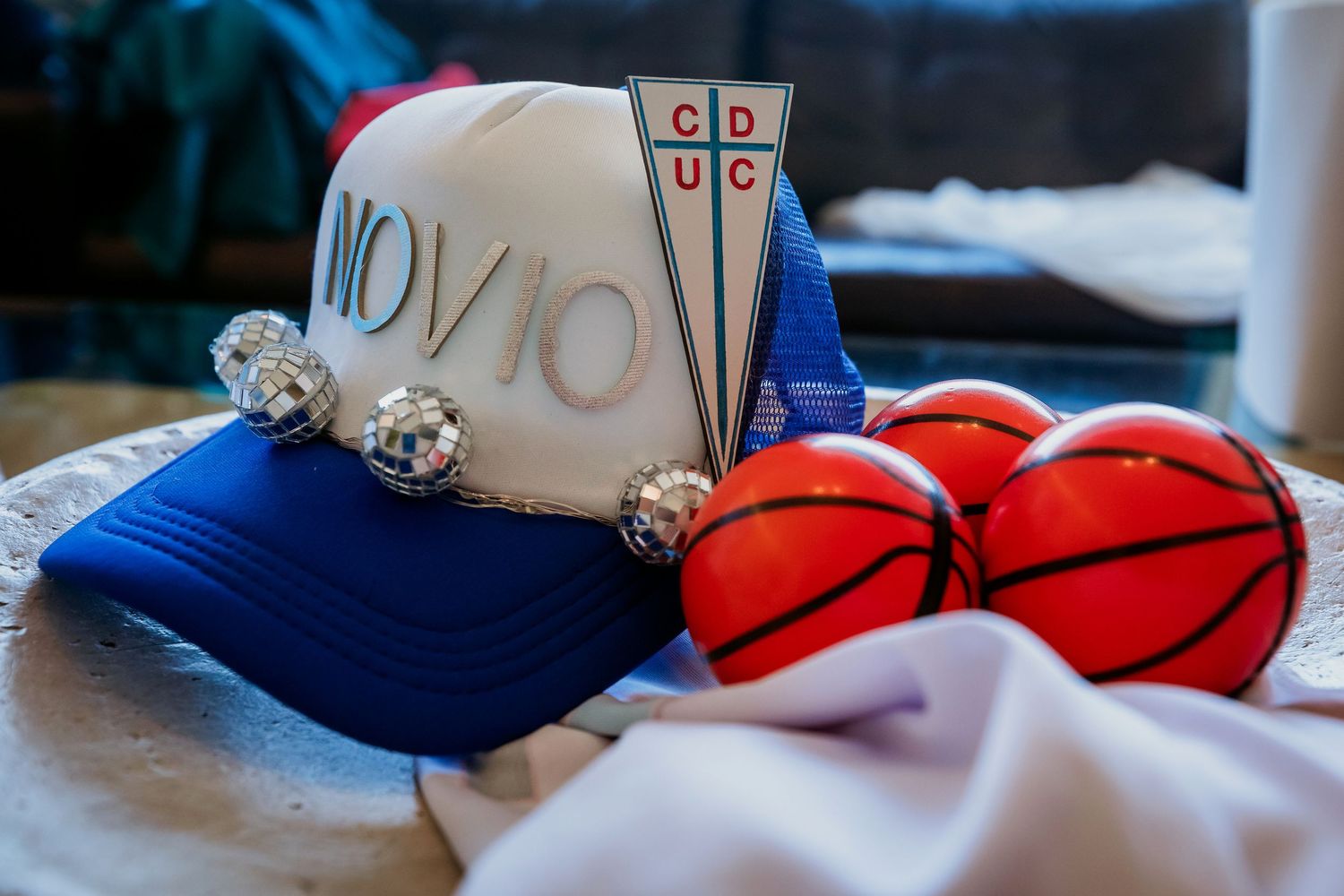 Blue trucker hat with NOV10 text and CDUC logo displayed with mini basketballs and disco balls.