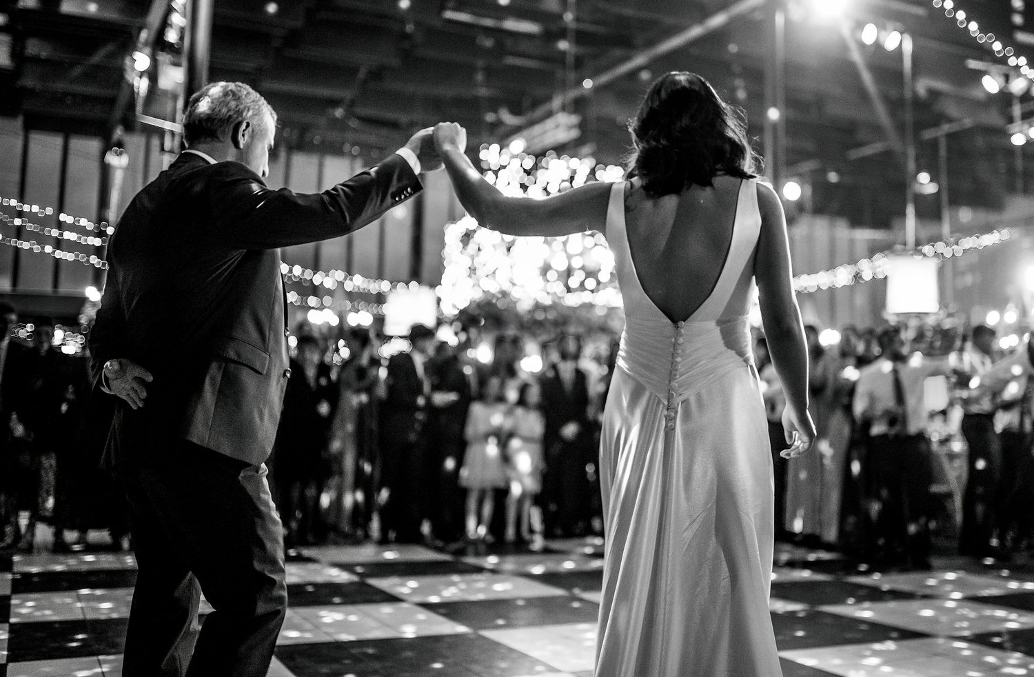 Black and white photo of a bride and groom sharing their first dance at an elegant wedding reception.