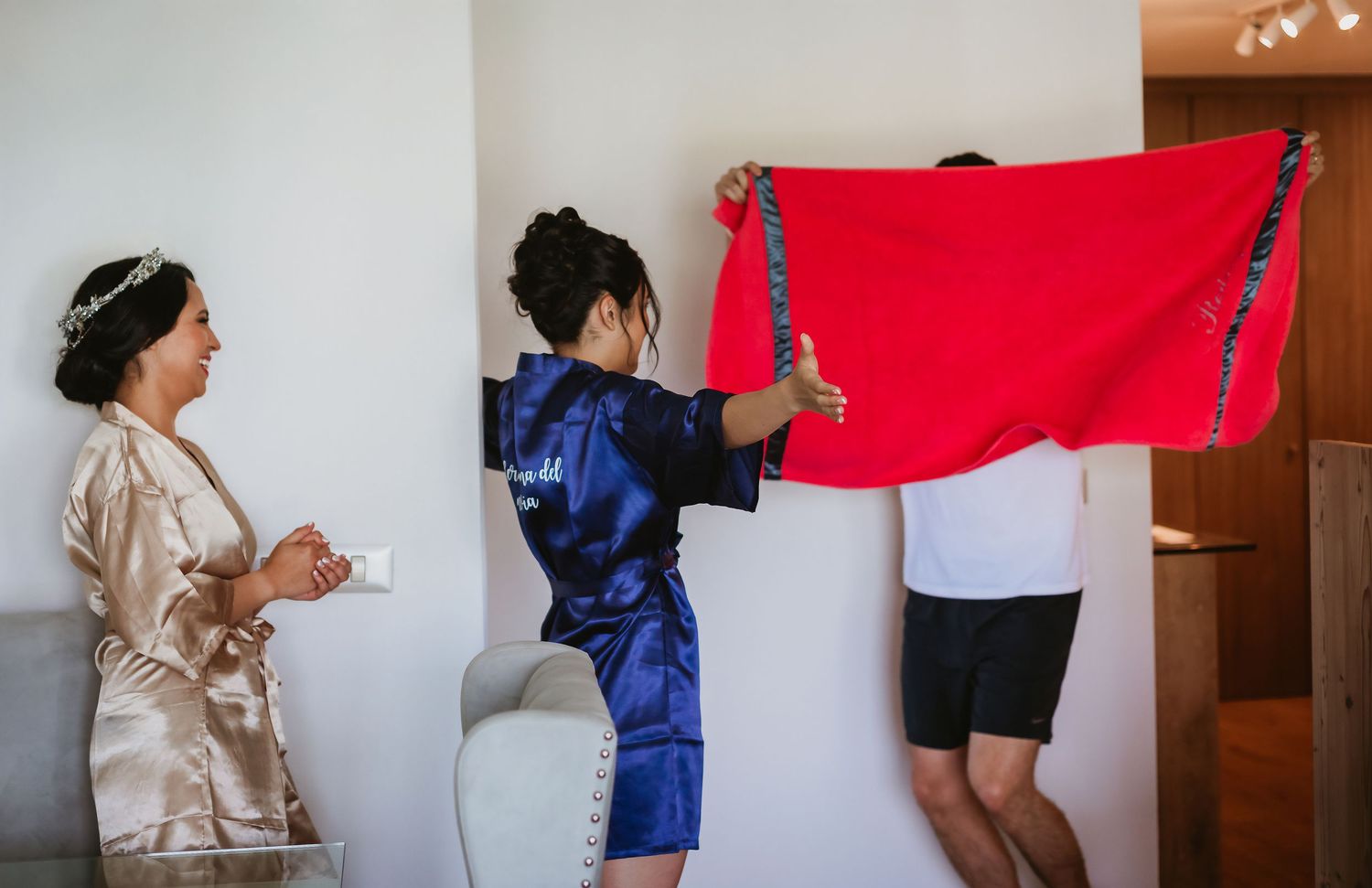 Bridesmaids in blue robes helping with wedding preparations indoors on the morning of the wedding.