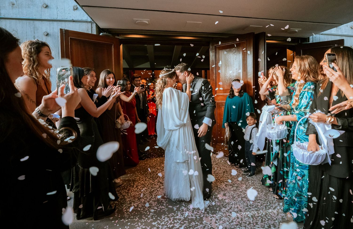 Newlyweds walk through a shower of white confetti as smiling guests celebrate their wedding exit.