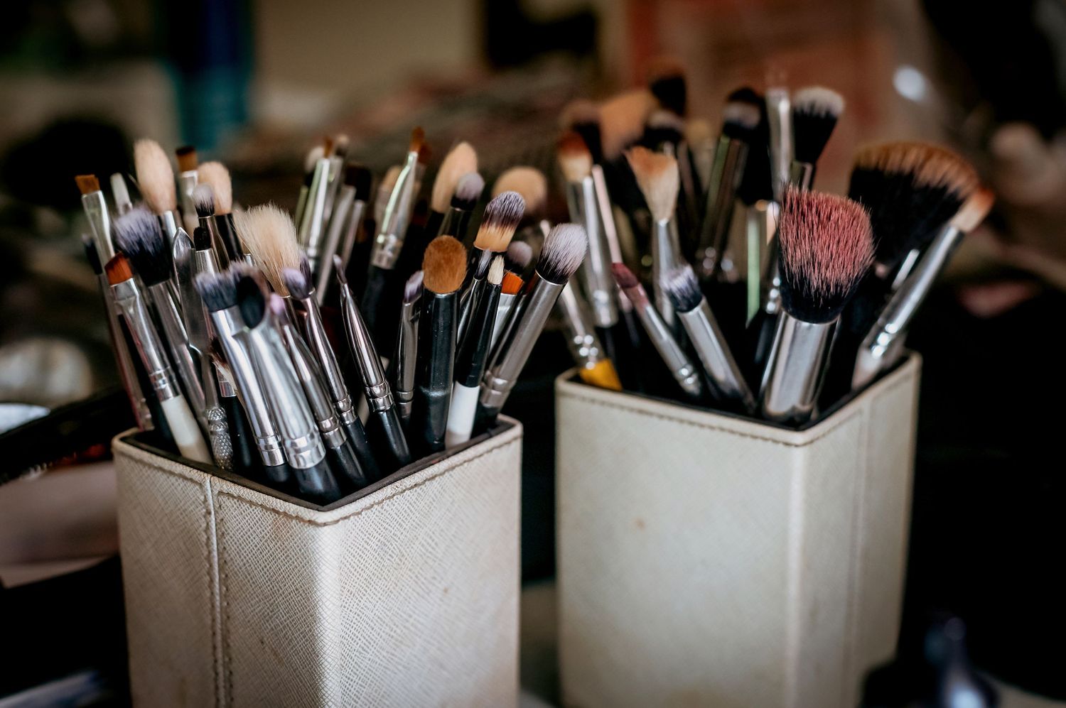 Collection of professional makeup brushes organized in square holders on vanity table.