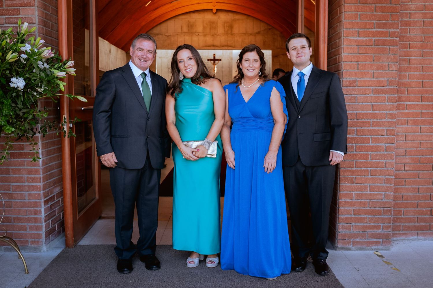 Family of four poses in formal attire outside a brick church entrance.